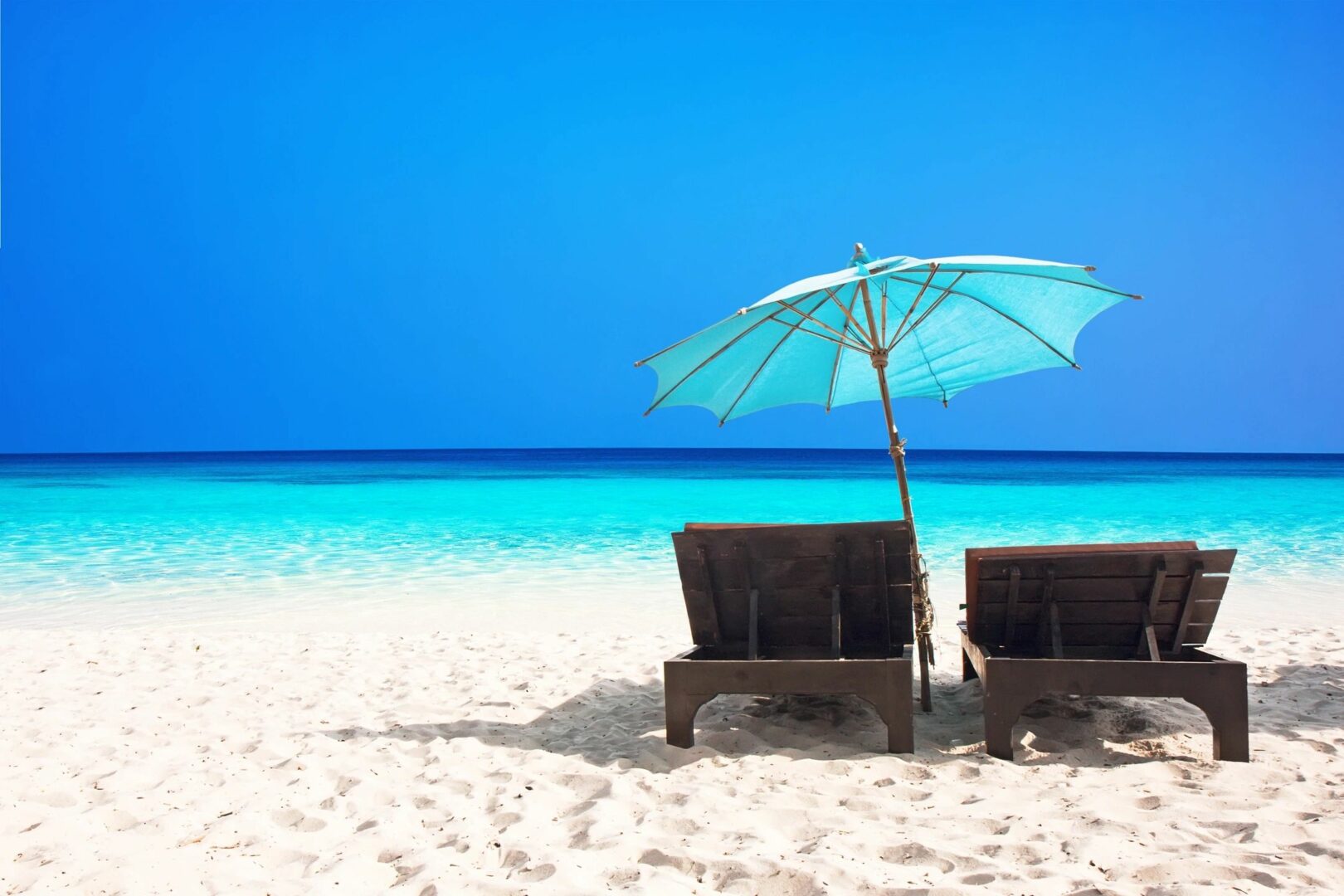 Two chairs and an umbrella on a beach.