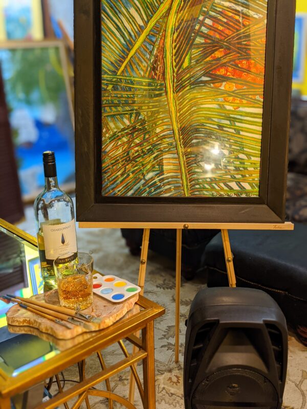 A painting of palm trees on canvas next to a glass bottle and wine.